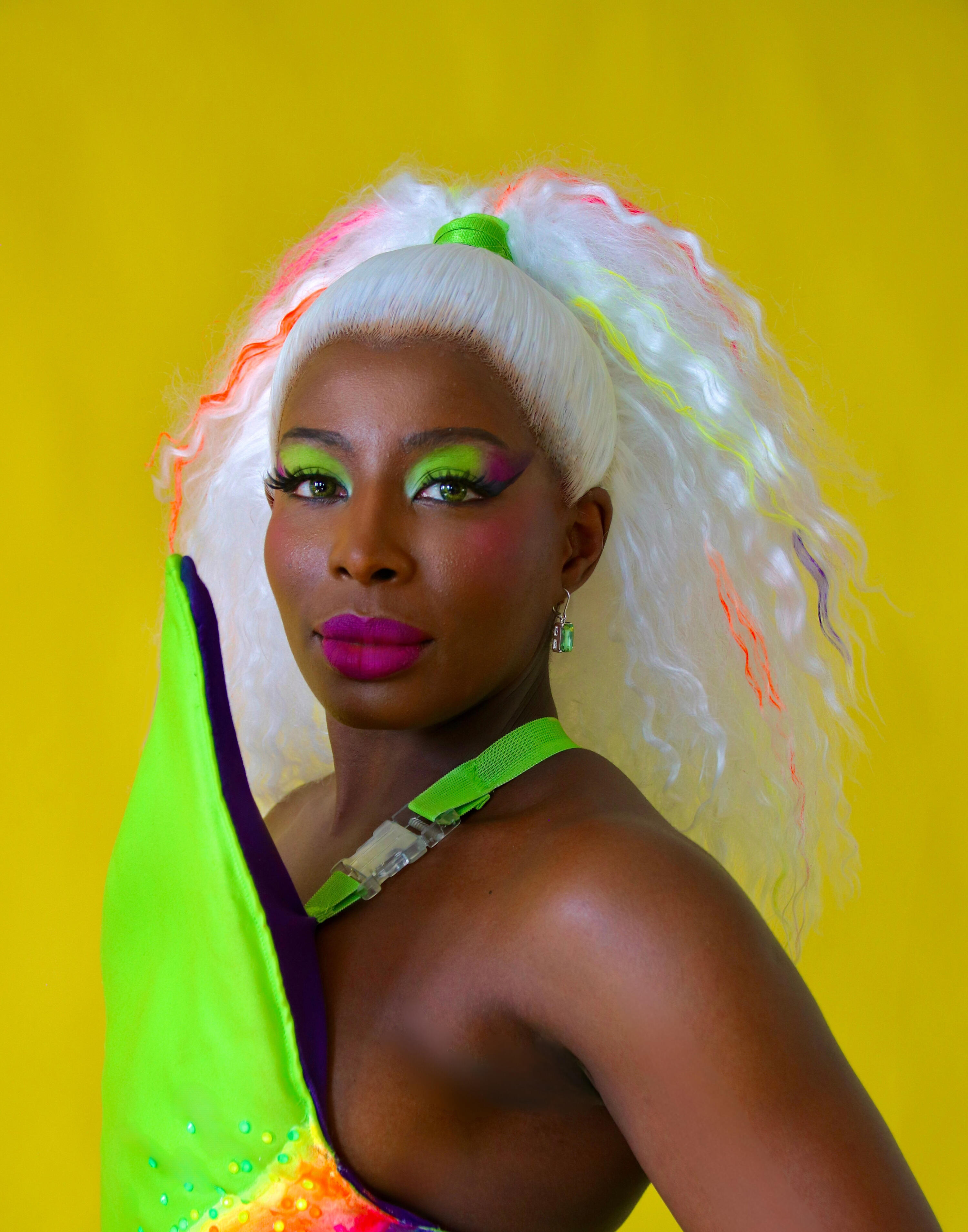 Red Tongued Raven wearing a green burlesque costume with colourful makeup